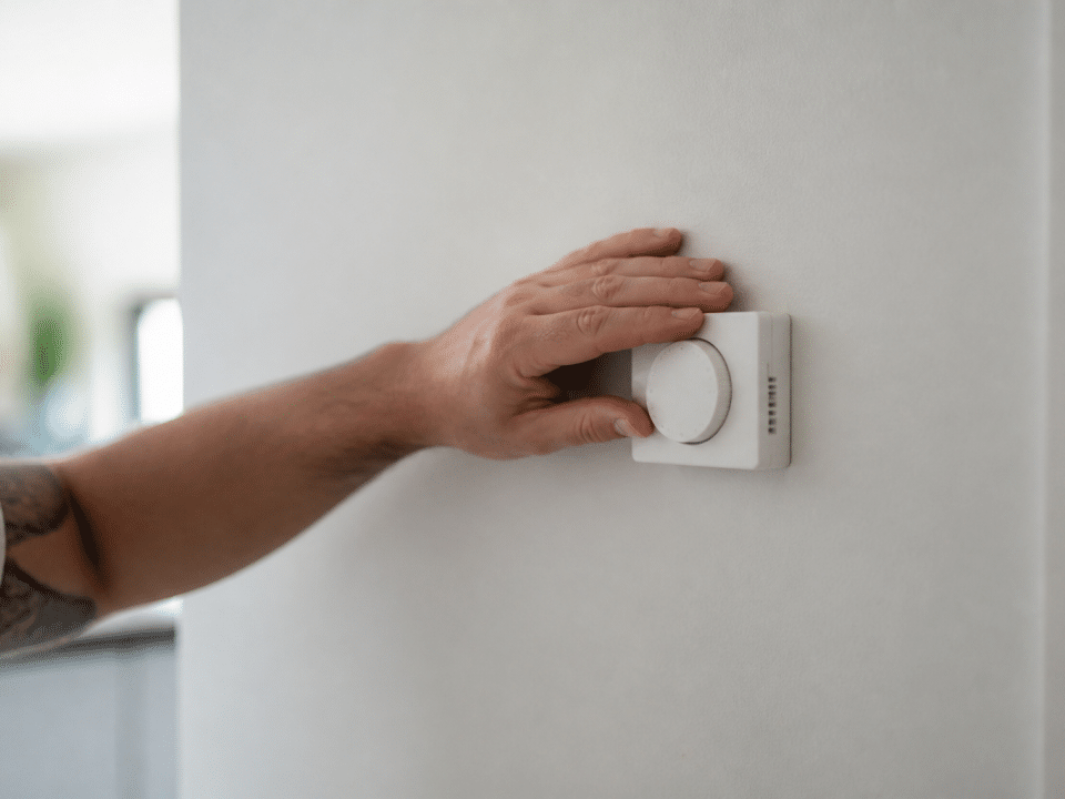 Thermostat mural baisse avec main posee dessus geste economie