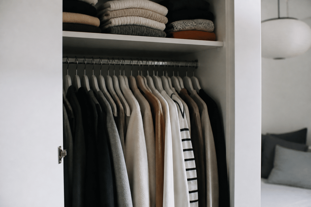 Vetements plies organises dans placard blanc avec cintres