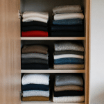 Vetements plies en piles organisees verticalement dans placard ouvert